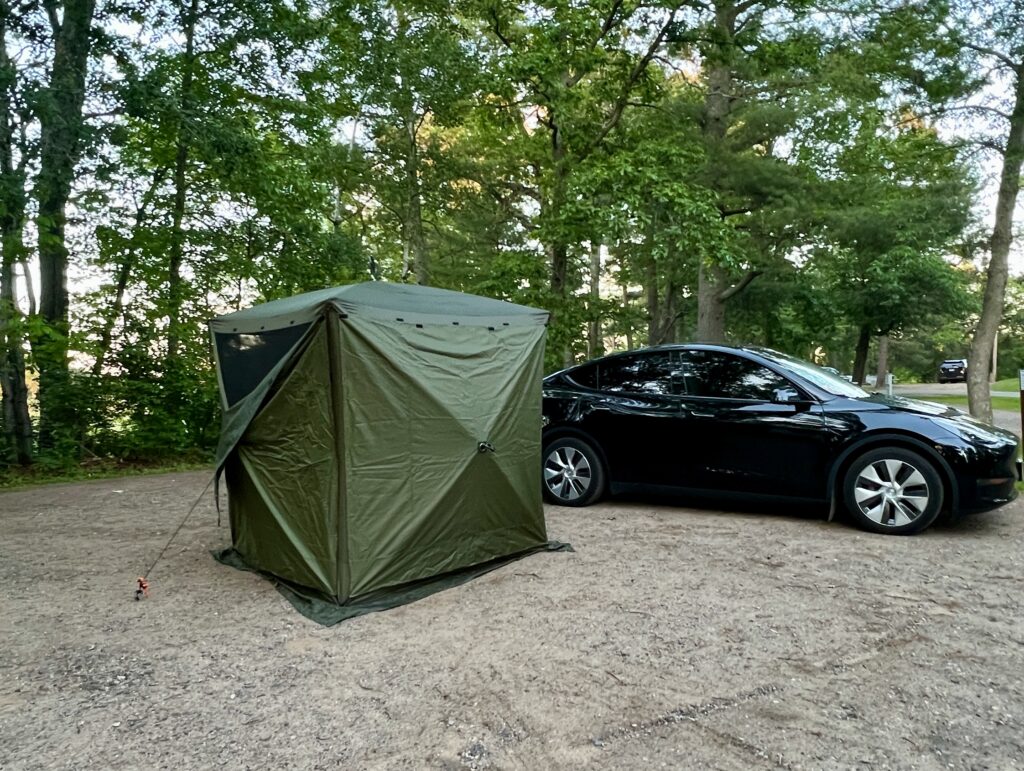 Clam quickset traveller tent set up next to car at campsite.