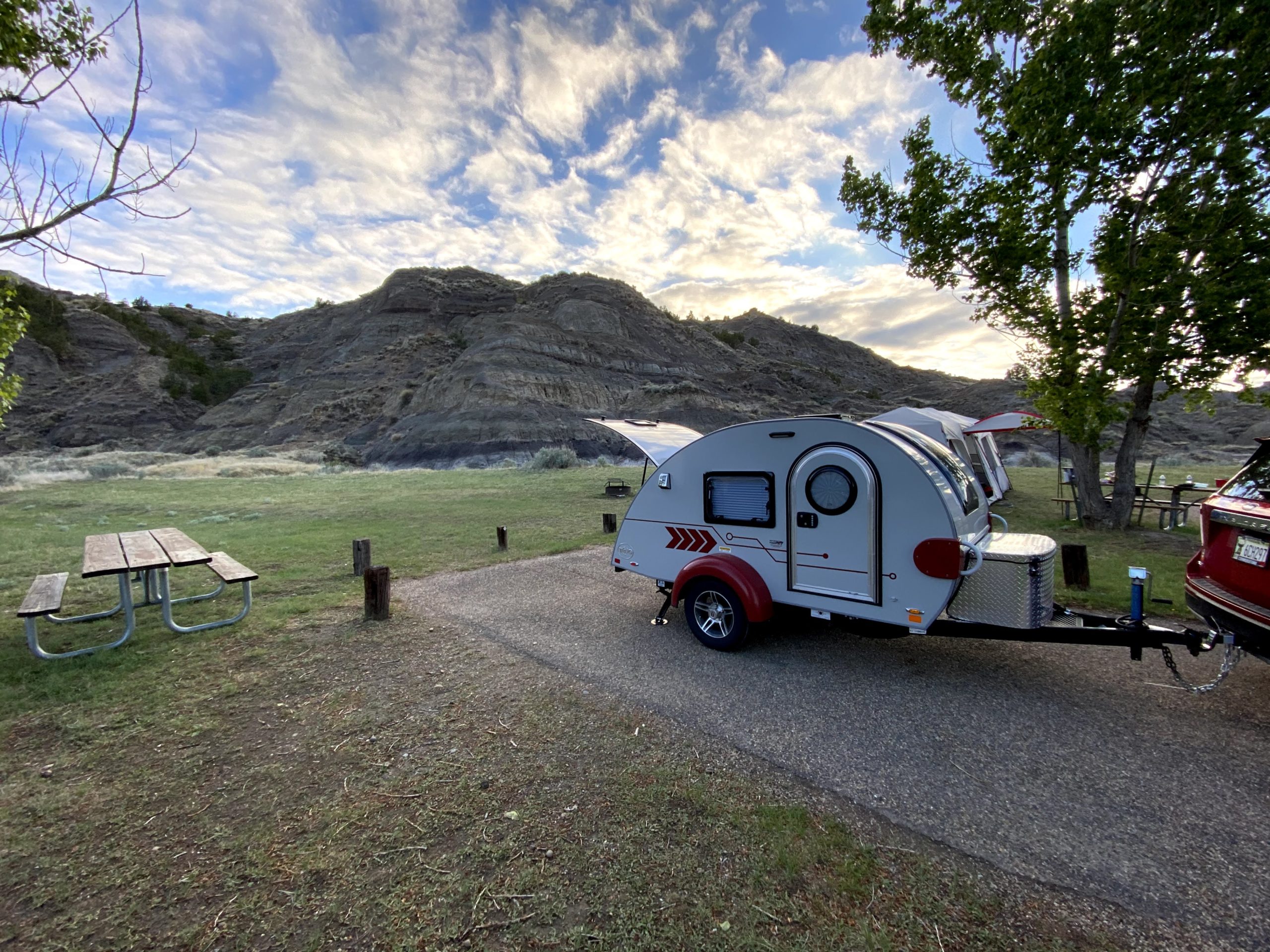 A teardrop trailer at a camp site in front of mountains