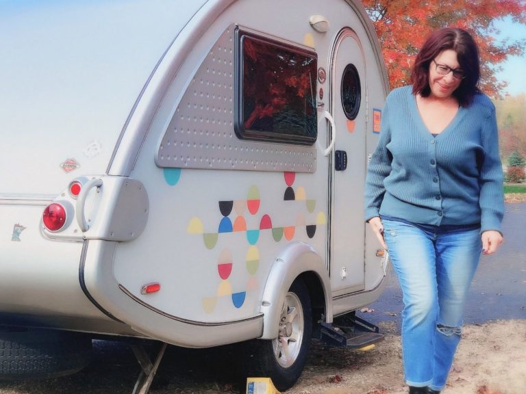 Woman standing next to teardrop camper