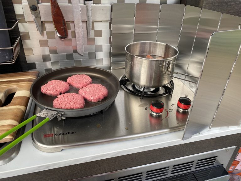 Hamburgers cooking on camper stovetop