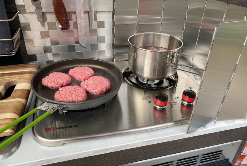 Hamburgers cooking on camper stovetop